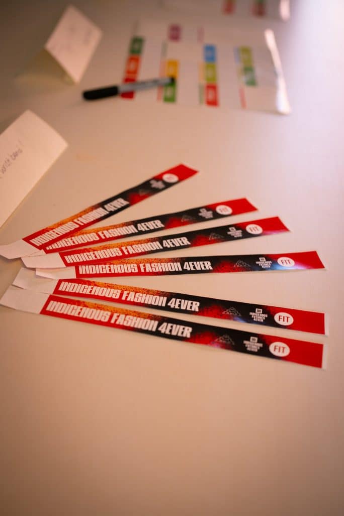 Indigenous Fashion 4EVER lanyards and event materials on a table