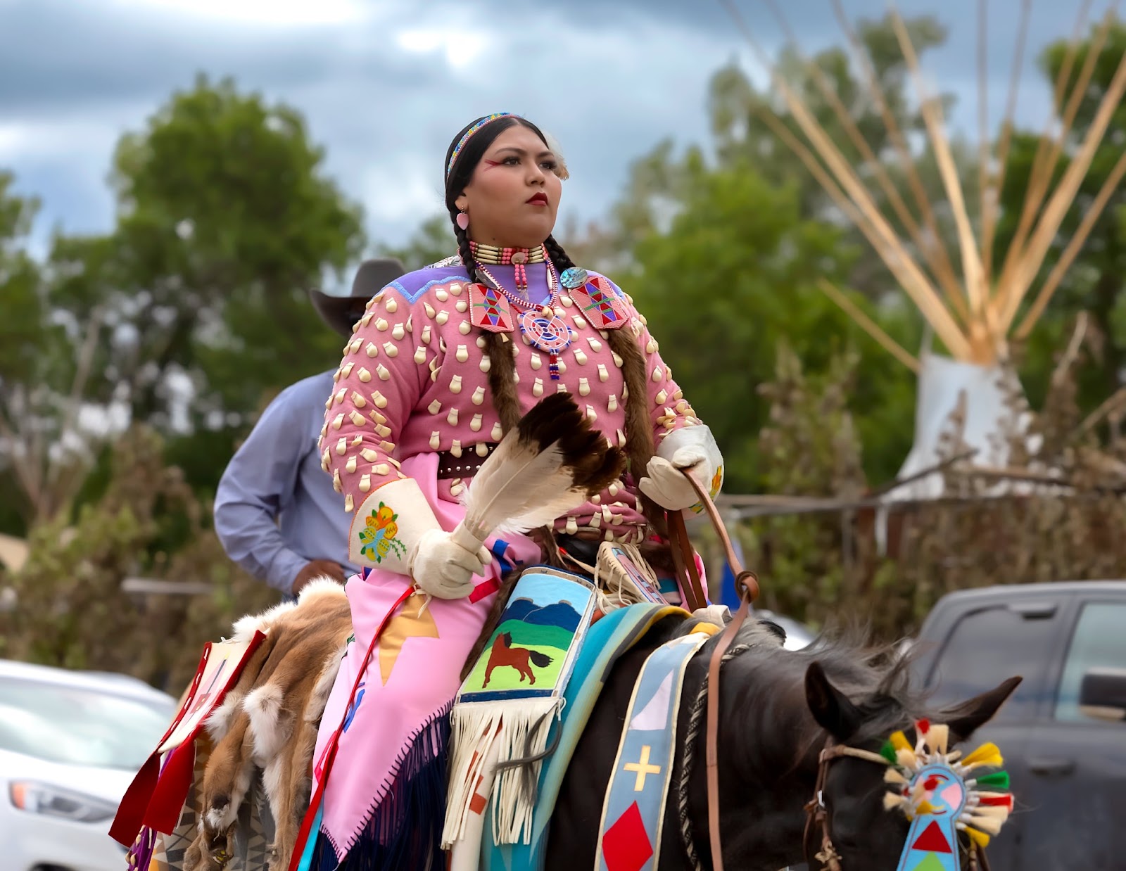 Apsáalooke woman on horseback in pink floral beadwork regalia at the Crow Fair Parade.