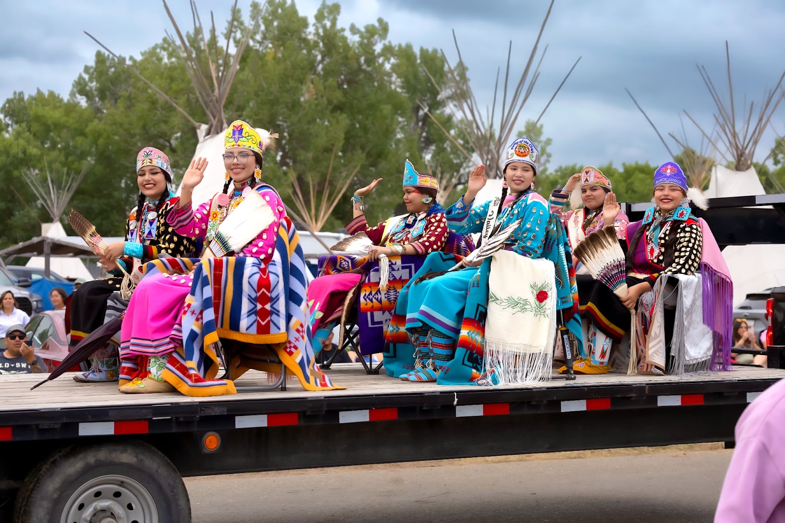 Group of Apsáalooke women in coordinated pink, blue and teal regalia in the Crow Fair Parade.
