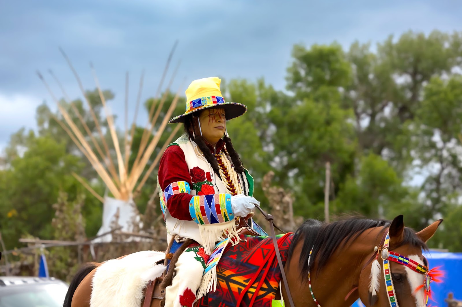 Apsáalooke woman in a black hat and beaded regalia riding in the Crow Fair Parade.